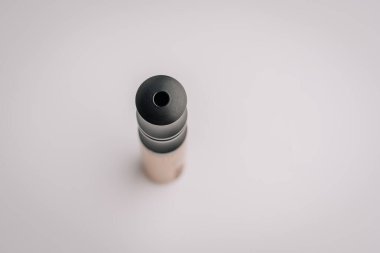 Tahta bir gövdeye monte edilmiş, yumuşak beyaz bir arkaplan üzerine kurulmuş siyah bir yelken ağızlığının yukarıdan aşağı makro görüntüsü..