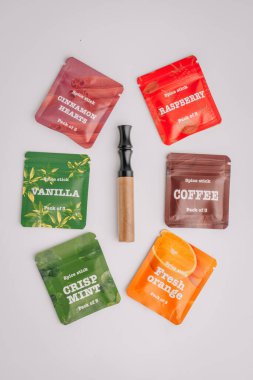Vanilya, ahududu, kahve ve beyaz arka planda nane aromalı altı renkli baharat çubuğu paketiyle çevrili ahşap bir aletin yukarıdan görünüşü..