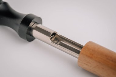 Siyah bir ağızlık ile beyaz bir arka planda ahşap bir kol arasındaki iç metal bölmeyi gösteren kısmen parçalanmış bir tüp cihazının yakın çekimi..