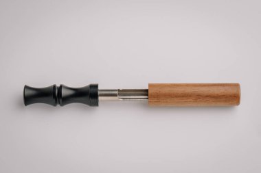 Siyah bir ağızlık, açıkta bırakılmış metal bölme ve temiz beyaz arka planda izole edilmiş ahşap saplı bir cihaz görüntüsü..