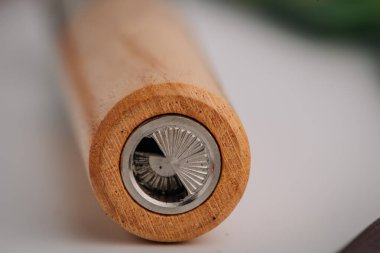 Tarafsız bir arkaplanda iç metal öğütücü mekanizmasının detaylı bir görüntüsünü gösteren ahşap bir yelpaze cihazının aşırı yakın çekimi.