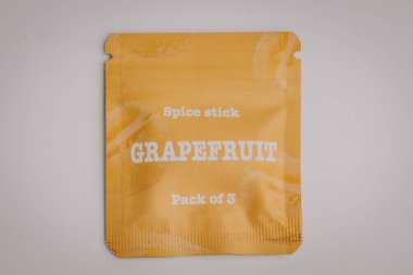 Üzerinde GRAPEFRUIT 3 etiketli sarı baharat paketi ince greyfurt dilimli grafikler, temiz, açık arkaplan üzerine yerleştirilmiş
