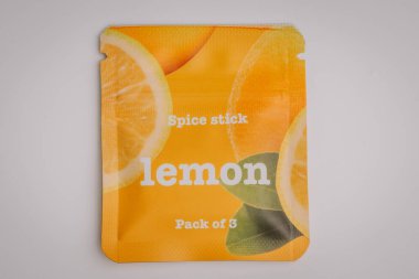 Üzerinde 3 'lü limon etiketli parlak sarı baharat paketi canlı narenciye dilimleri ve temiz ve minimal bir arkaplan