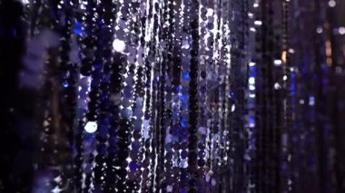 Yansıyan mavi ve gümüş ışıklarla parıldayan koyu pullu perdelerin yakın çekimi, olay aydınlatması altında büyüleyici dokulu bir etki yaratır..