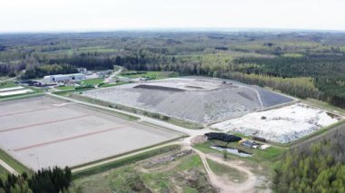 Kudumlar, Letonya - 28 Nisan 2025 - Toprak depolama, geri dönüşüm alanları, yeşil bölgeler ve çevreleyen orman içeren modern bir atık yönetim tesisinin havadan görünüşü.