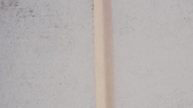 Dar bir merkez siper ya da bölücüye sahip açık kum renkli bir yüzeyin dikey, minimum doku ve ayrıntılarla hava yakın görüntüsü.