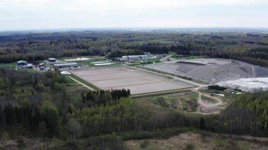 Kudumlar, Letonya - 28 Nisan 2025 - Ormanla çevrili büyük bir atık yönetimi ve atık depolama tesisinin havadan görüntüsü, aktif ve pasif atık bölgeleri ve tedavi altyapısını gösteriyor.