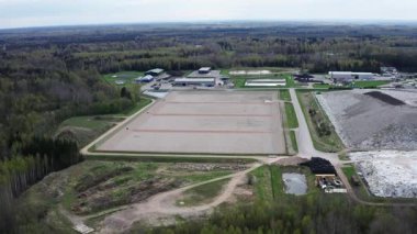 Kudumlar, Letonya - 28 Nisan 2025 - Ormanla çevrili büyük bir atık yönetimi ve atık depolama tesisinin havadan görüntüsü, aktif ve pasif atık bölgeleri ve tedavi altyapısını gösteriyor.