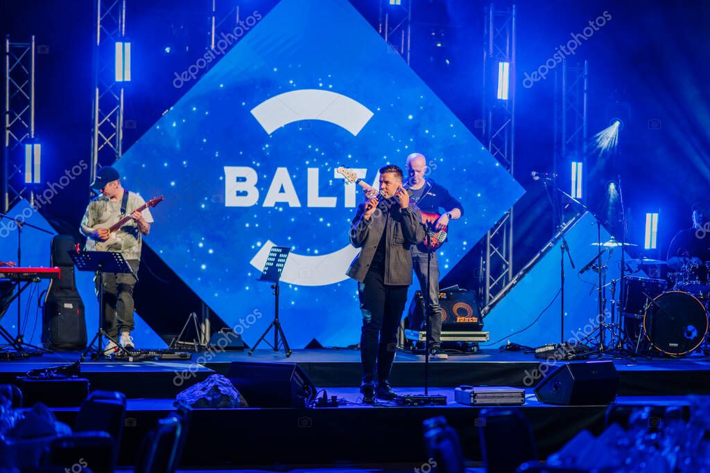 Riga, Latvia - April 26, 2025 - Live music performance on stage at a Balta event, with musicians, instruments, and bright blue cosmic-themed visuals and lighting.