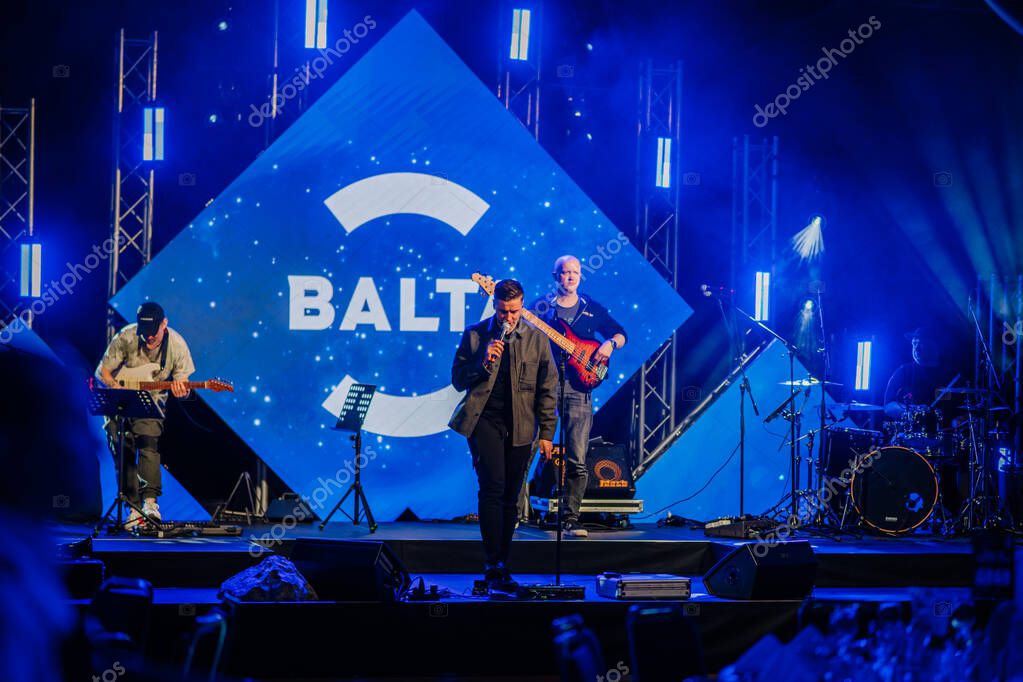 Riga, Latvia - April 26, 2025 - Live music performance on stage at a Balta event, with musicians, instruments, and bright blue cosmic-themed visuals and lighting.
