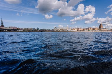 Riga, Letonya - 3 Mayıs 2025 - Rigas 'ın Daugava Nehri' nden gökyüzü bulutlu bir gökyüzü altında merkezi pazar hangarları ve Letonya Bilimler Akademisi 'nin yer aldığı panoramik görünümü