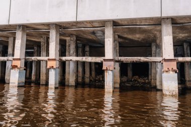 Riga, Letonya - 3 Mayıs 2025 - Deniz kenarındaki bir yapının beton sütunları destek kirişlerini ve yıpranmış yüzeyleri gösteriyor.