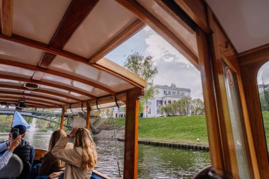 Riga, Letonya - 3 Mayıs 2025 Turistler Litvanya 'nın Riga şehrinde deniz manzaralı bir tekne turunun keyfini çıkarıyorlar..