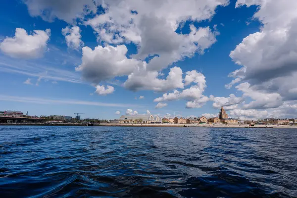 Riga, Letonya - 3 Mayıs 2025 - Rigas 'ın Daugava Nehri' nden gökyüzü bulutlu bir gökyüzü altında merkezi pazar hangarları ve Letonya Bilimler Akademisi 'nin yer aldığı panoramik görünümü