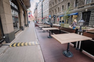 Riga, Letonya - 3 Mayıs 2025 - Avrupa 'nın tarihi mimarisi ve en az yaya trafiğine sahip bir şehrinde kaldırım taşı caddesi boyunca boş bir kafeterya oturma alanı