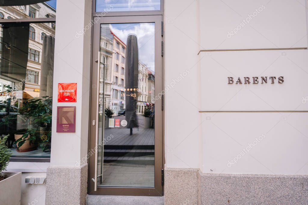 Riga, Latvia - May 3, 2025 - Street-level view of a modern restaurant entrance with Barents signage and a red 2025 Michelin plaque mounted beside the glass door