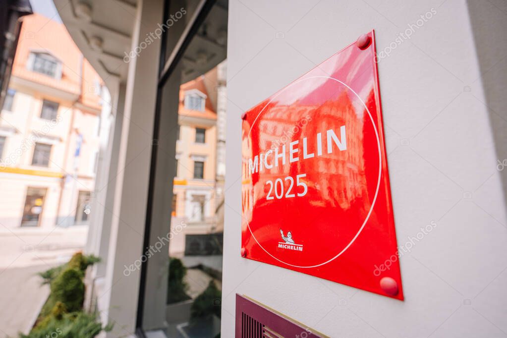 Riga, Latvia - May 3, 2025 - Angled view of a red MICHELIN 2025 plaque on a wall outside a restaurant, signifying prestigious culinary recognition
