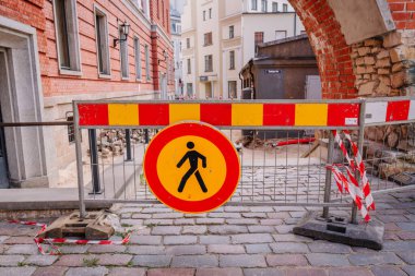 Riga, Letonya - 3 Mayıs 2025 - kaldırım taşı caddesinde kaldırım taşı levhası ve bariyeri olan kentsel inşaat alanı, bürokrasi ve tarihi binalarla çevrili.