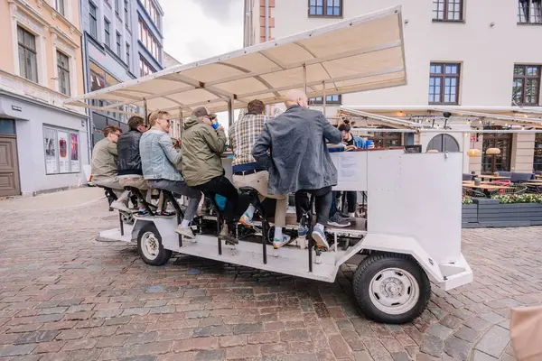 3 Mayıs 2025 - Riga, Letonya 'da kaldırım taşı caddelerinde gezen bir grup insan tepe örtüsü altında sosyalleşirken pedal çeviriyor..