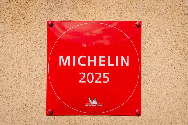 Riga, Letonya - 3 Mayıs 2025 - Bej kaplama duvara asılmış kırmızı Michelin 2025 plaketi aşçılık mükemmelliğini ve restoran tanınmasını temsil ediyor.