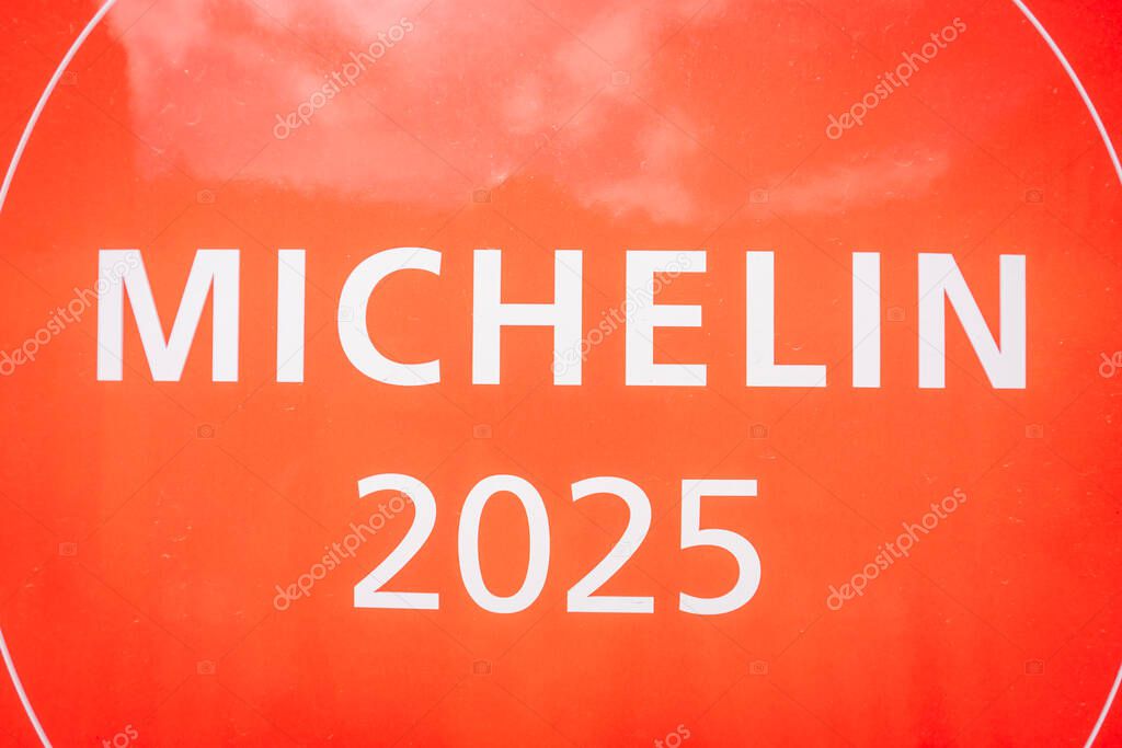 Riga, Latvia - May 3, 2025 - Extreme close-up of a red Michelin 2025 plaque showing the bold white text, symbolizing prestigious restaurant recognition and culinary excellence.