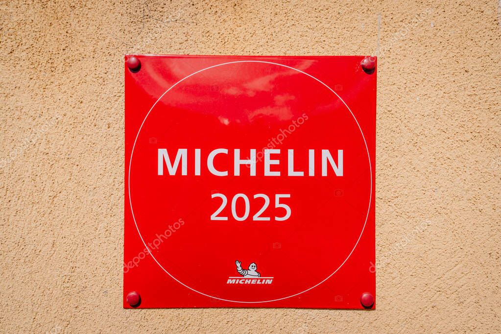Riga, Latvia - May 3, 2025 - Close-up of a red Michelin 2025 plaque mounted on a beige stucco wall, representing culinary excellence and restaurant recognition.