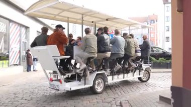 Riga, Letonya - 3 Mayıs 2025 - Bir grup insan Rigas Old Town 'da bir kaldırım taşı caddesinde pedallı bira bisikletine binip sosyal turun tadını çıkarıyorlar..