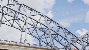 Riga, Letonya - 3 Mayıs 2025 - Kamera Riga 'daki bir demiryolu köprüsünün altından hareket ederken çelik yapının yakın çekim görüntüleri, mimari ayrıntıları ve kentsel altyapıyı yakalıyor..