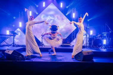 Riga, Letonya - 26 Nisan 2025 - BALTA 'da üç dansçı, biri bale eteği ve astronot kaskı içinde, baleyi uzay temalı zarafet ve tiyatro hareketleriyle harmanlıyor.