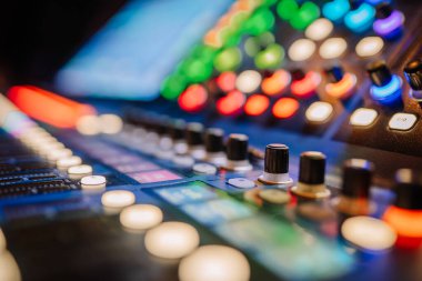 Valmiera, Letonya - 8 Mayıs 2025 - Profesyonel bir ses karıştırıcı konsolunun düğmeleri, düğmeleri ve canlı ses ortamında aydınlatılmış kontrolleri içeren renkli bir yakın plan.