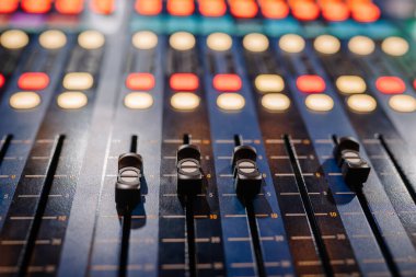 Valmiera, Letonya - 8 Mayıs 2025 - Profesyonel bir ses stüdyosundaki ses karıştırma panolarının fişleri ve düğmeleri, kaydırma kontrolleri ve arka ışıklandırma düğmeleri üzerine seçici odaklı.