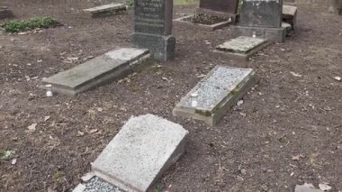 Cesis, Letonya - Ekim 12, 2024 - Bulutlu bir günde arka planda eski mezar taşları, mumlar, çıplak ağaçlar ve evler bulunan Letonya 'daki Yahudi mezarlığına geniş bir bakış açısı.