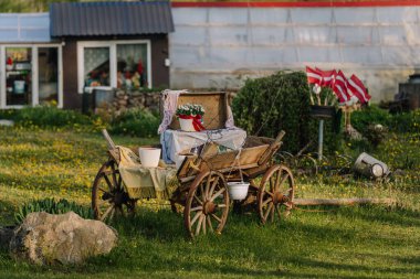 Smiltene, Letonya - 17 Mayıs 2025 - Arka planda çimenli bir bahçe, Letonya bayrakları ve kırsal bir ev.