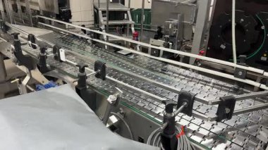Valmiera, Letonya - 17 Mayıs 2025 - Otomatik üretim ve etiketleme hattı boyunca şişeleri taşımak için tasarlanmış içecek şişeleme tesisinde paslanmaz çelik taşıma sistemi.