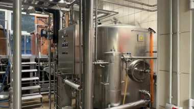 Valmiera, Letonya - 17 Mayıs 2025 - Temiz endüstriyel altyapı sergilenen bira fabrikası veya gıda işleme tesisinde paslanmaz çelik tanklar, borular ve kontrol paneli.