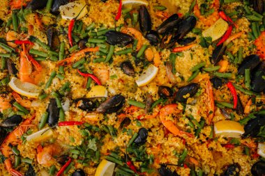 Karidesli, midyeli, limonlu, yeşil fasulyeli ve büyük bir tavada kırmızı biberli canlı deniz ürünleri paella 'sı..