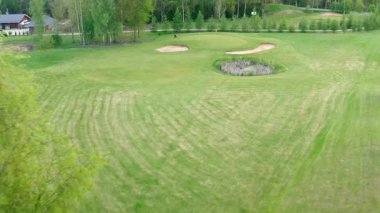 Valmiera, Letonya - 21 Mayıs 2025 - İnsansız hava aracı, yemyeşil bir bölgeye yaklaşan bir golfçüyü görüntüledi..