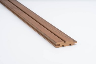 Beyaz arka planda görünen derin paralel oyukları olan kahverengi ahşap çizgili bir profil. Akustik paneller, kaplama veya modern mimari tasarım için ideal.