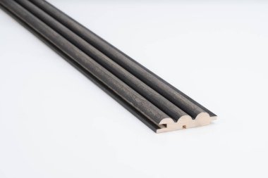 Beyaz arka plana yerleştirilmiş, üç katlı çıkıntılı ve doğal ahşap kenarlı siyah ahşap kaplama. Dekoratif duvar panelleri veya akustik kullanım için uygun.