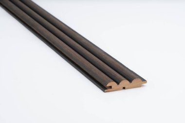 Koyu kahverengi ahşap kaplama, üçlü yuvarlak çıkıntılar ve hassas oyuklar, beyaz arka planda gösteriliyor. Akustik panel ya da duvar dekorasyonu için tasarlandı.