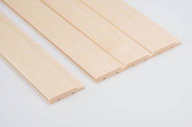 Beyaz arka planda yan yana dizilmiş ince kıvrımlı oyuk profilleri olan hafif ahşap levhalar. Dekoratif veya akustik duvar kurulumları için tasarlandı.