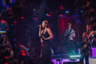 Valmiera, Letonya - 22 Mayıs 2025 - Siyah elbiseli kadın şarkıcı canlı müzik grubu ve Yamaha klavyesiyle canlı performans sergiliyor..