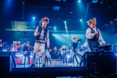Valmiera, Letonya - 22 Mayıs 2025 - Yüksek enerji ve canlı enstrümanlarla sahne alan çocuklar, renkli bir konser ortamında Yamaha klavyesi ve gitarlarıyla.