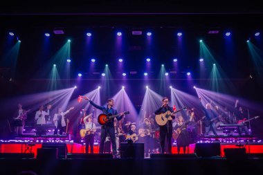 Valmiera, Letonya - 22 Mayıs 2025 - Mor ışıklar altında gitaristlerle ve koroyla tam sahne konseri, Yamaha enstrümanlarıyla birlikte canlı, işbirlikçi bir performans sergilediler..