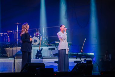 Valmiera, Letonya - 22 Mayıs 2025 - İki kadın şarkıcı sahne ışıkları altında mikrofonlar, Yamaha klavyesi, elektro gitarlar ve canlı bir konser ortamında görülen davullarla performans sergiliyorlar.