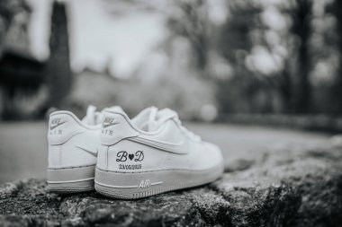 Valmiera, Latvai - 23 Mayıs 2025 Nike Air 'in baş harfleri ve düğün tarihli siyah beyaz ayakkabıları kırsal taştan bir yüzeye yerleştirilmiş..