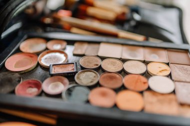 Renkli, iyi kullanılmış bir makyaj paletinin yakın plan görüntüsü. Pudra, kızarıklık ve göz farı çeşitli tonlarda..