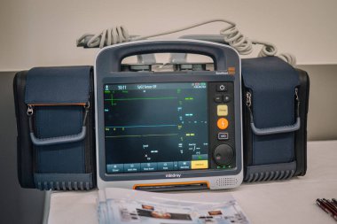 Valmiera, Letonya - 31 Mayıs 2025 - Mindray BeneHeart D60 defibrilatör monitörünün kablolar ve yan keselerle yakın çekimi, tıbbi bir kurulum sırasında ekranda hayati bulguları gösteriyor.