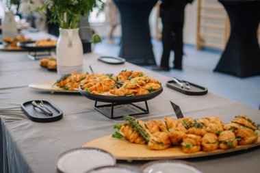 Açık büfe masasında kruvasan sandviçler ve tabaklar halinde otlar, açık bir mekanda bir etkinlik ya da yemek servisi için hazırlandı..