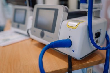 Valmiera, Letonya - 31 Mayıs 2025 - Tahta bir masada mavi kablo bağlantısı, kontrol ekranı ve sarı açma düğmesini gösteren tıbbi bir MIRUS vantilatör cihazının yakın çekimi.